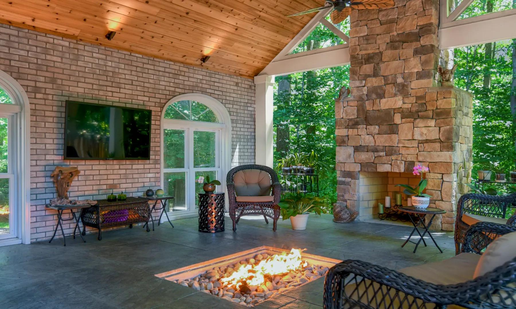 Covered stone-and-cedar porch with a fireplace and fire pit, built by MJCI in Clifton, Virginia